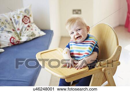 Stock Image - Baby Boy Sitting In High Chair. Fotosearch
