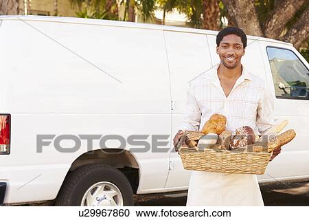 Stock Image - Baker Delivering Bread Standing In Front Of Van. Fotosearch