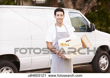 Stock Image - Baker Delivering Cakes Standing In Front Of Van. Fotosearch