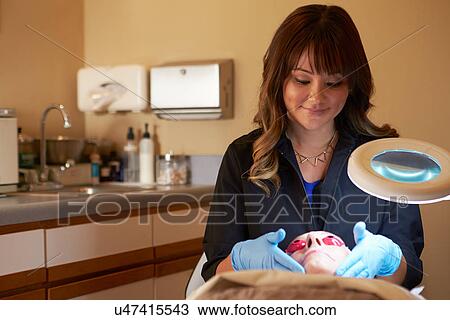 Stock Image - Beautician Applying Cream To Female Client In Clinic. Fotosearch