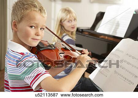 Stock Photo - Boy and girl playing violin and piano at home. Fotosearch