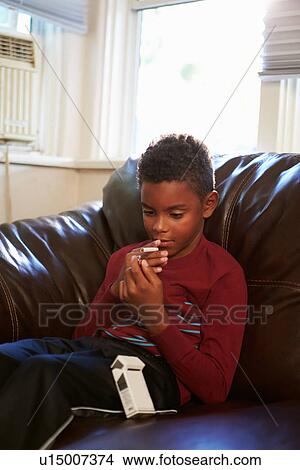 Picture - Boy Discovering Parent's Pack Of Cigarettes At Home. Fotosearch