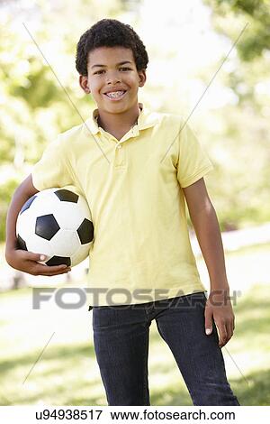 Boy in park holding football View Large Photo Image Stock Photo - Boy in park holding football. Fotosearch