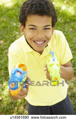 Boy in park with water pistols View Large Photo Image Stock Image - Boy in park with water pistols. Fotosearch