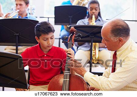 Stock Image - Boy Learning To Play Cello In High School Orchestra. Fotosearch
