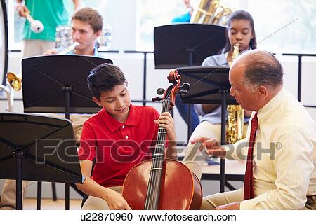 Stock Image - Boy Learning To Play Cello In High School Orchestra. Fotosearch