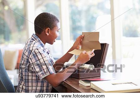 Stock Image - Boy Looking At Letter In Keepsake Box On Desk. Fotosearch