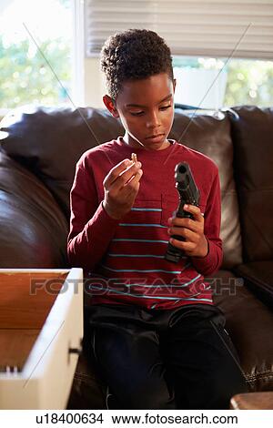 Picture - Boy Playing With Parent's Gun He Has Found At Home. Fotosearch
