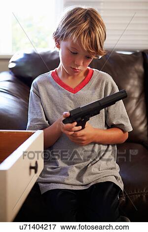 Stock Photo - Boy Playing With Parent's Gun He Has Found At Home. Fotosearch