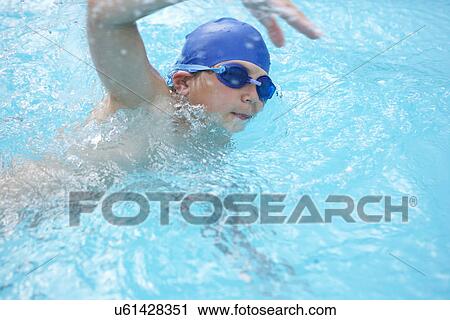 Stock Image - Boy swimming in outdoor pool. Fotosearch