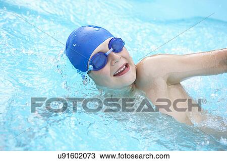 Stock Image - Boy swimming in outdoor pool. Fotosearch