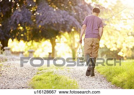 Stock Photo - Boy Walking Along Path Carrying Fishing Net And Jar. Fotosearch