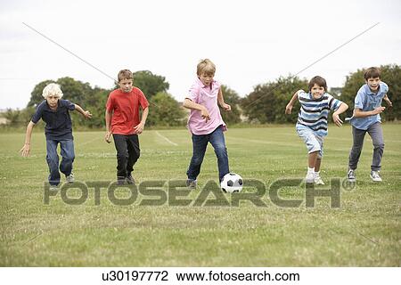 Stock Image - Boys playing with football in park. Fotosearch