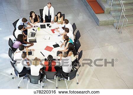 Stock Photograph - Businessman Addressing Meeting Around Boardroom Table. Fotosearch
