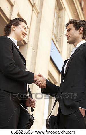 Businessman and business woman shaking hands outside building View Large Photo Image Stock Photography - Businessman and business woman shaking hands outside building. Fotosearch
