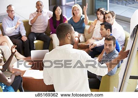 Stock Image - Businessman Making Presentation To Office Colleagues. Fotosearch