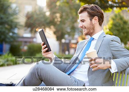 Businessman On Park Bench With Coffee Using Digital Tablet View Large Photo Image Picture - Businessman On Park Bench With Coffee Using Digital Tablet. Fotosearch