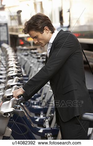 Stock Image - Businessman using hire bike. Fotosearch