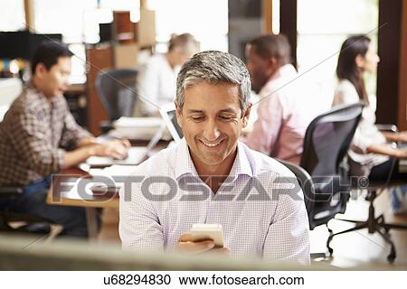Businessman Working At Desk Using Mobile Phone View Large Photo Image Stock Image - Businessman Working At Desk Using Mobile Phone. Fotosearch
