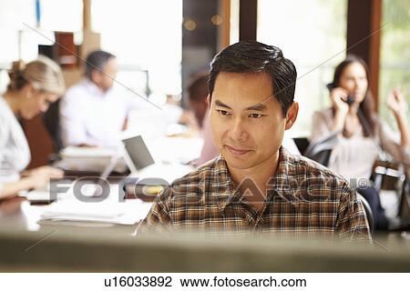 Businessman Working At Desk With Meeting In Background View Large Photo Image Stock Image - Businessman Working At Desk With Meeting In Background. Fotosearch