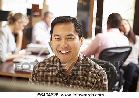 Businessman Working At Desk With Meeting In Background View Large Photo Image Stock Photo - Businessman Working At Desk With Meeting In Background. Fotosearch
