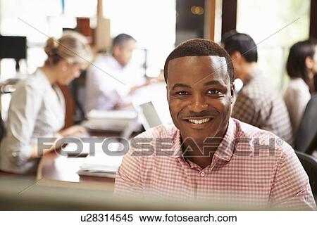 Businessman Working At Desk With Meeting In Background View Large Photo Image Stock Photography - Businessman Working At Desk With Meeting In Background. Fotosearch