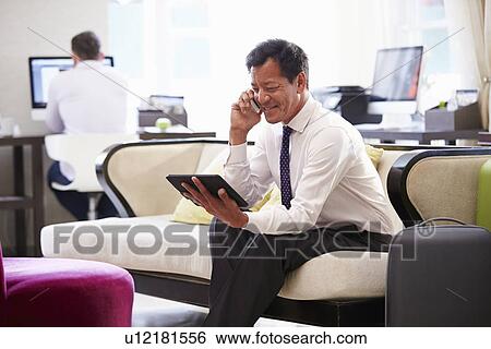 Businessman Working On Digital Tablet In Hotel Lobby View Large Photo Image Stock Photograph - Businessman Working On Digital Tablet In Hotel Lobby. Fotosearch