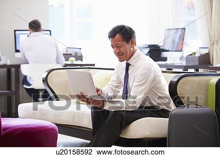 Businessman Working On Laptop In Hotel Lobby View Large Photo Image Stock Image - Businessman Working On Laptop In Hotel Lobby. Fotosearch