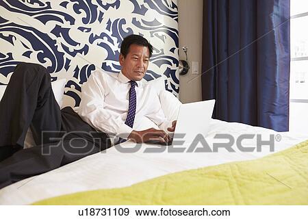 Stock Photo - Businessman Working On Laptop In Hotel Room. Fotosearch
