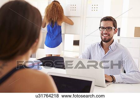 Businesspeople Using Laptop In Office Of Start Up Business View Large Photo Image Stock Photo - Businesspeople Using Laptop In Office Of Start Up Business. Fotosearch