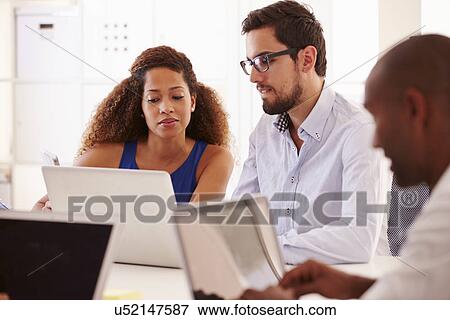 Businesspeople Using Laptop In Office Of Start Up Business View Large Photo Image Stock Photo - Businesspeople Using Laptop In Office Of Start Up Business. Fotosearch