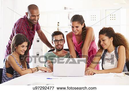 Stock Photo - Businesspeople Using Laptop In Office Of Start Up Business. Fotosearch