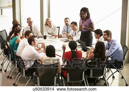 Picture - Businesswoman Addressing Meeting Around Boardroom Table. Fotosearch