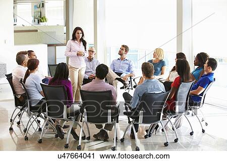 Stock Image - Businesswoman Addressing Multi-Cultural Office Staff Meeting. Fotosearch