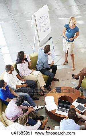 Stock Image - Businesswoman Making Presentation To Office Colleagues. Fotosearch