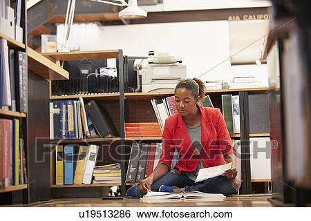 Stock Photograph - Businesswoman Sitting On Office Floor Reading Documents. Fotosearch