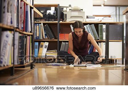 Stock Photograph - Businesswoman Sitting On Office Floor Reading Documents. Fotosearch