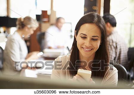 Businesswoman Working At Desk Using Mobile Phone View Large Photo Image Stock Photograph - Businesswoman Working At Desk Using Mobile Phone. Fotosearch