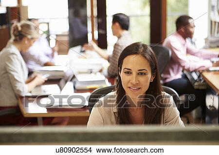 Businesswoman Working At Desk With Meeting In Background View Large Photo Image Picture - Businesswoman Working At Desk With Meeting In Background. Fotosearch
