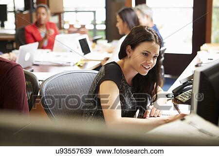 Businesswoman Working At Desk With Meeting In Background View Large Photo Image Stock Photo - Businesswoman Working At Desk With Meeting In Background. Fotosearch