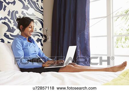 Stock Photo - Businesswoman Working On Laptop In Hotel Room. Fotosearch