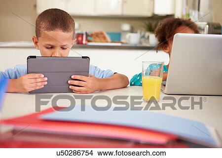 Picture - Children Using Laptop And Digital Tablet To Do Homework. Fotosearch