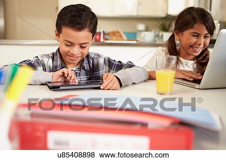 Children Using Laptop And Digital Tablet To Do Homework View Large Photo Image Stock Photo - Children Using Laptop And Digital Tablet To Do Homework. Fotosearch