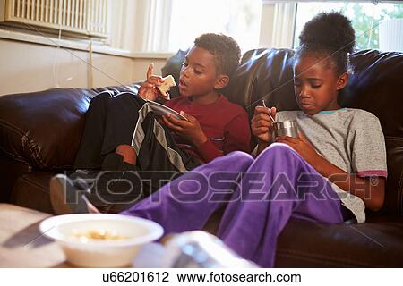 Children With Poor Diet Eating Meal On Sofa At Home View Large Photo Image Stock Image - Children With Poor Diet Eating Meal On Sofa At Home. Fotosearch