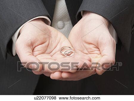 Stock Photo - Close Up Of Groom Holding Wedding Rings. Fotosearch