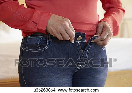 Picture - Close Up Of Overweight Woman Trying To Fasten Trousers. Fotosearch