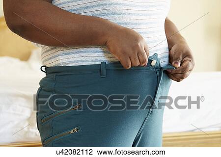 Stock Image - Close Up Of Overweight Woman Trying To Fasten Trousers. Fotosearch