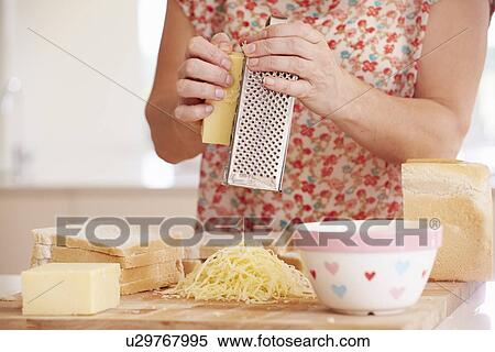 Stock Photography - Close Up Of Woman Grating Cheese In Kitchen. Fotosearch