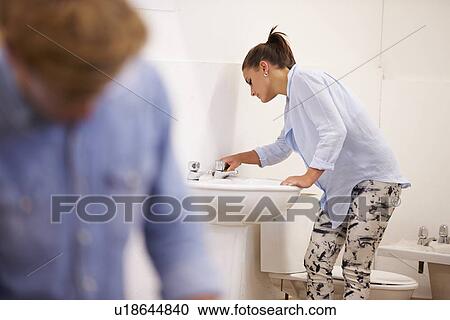 Stock Image - College Students Studying Plumbing Working On Washbasin. Fotosearch