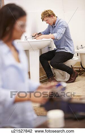 Stock Image - College Students Studying Plumbing Working On Washbasin. Fotosearch